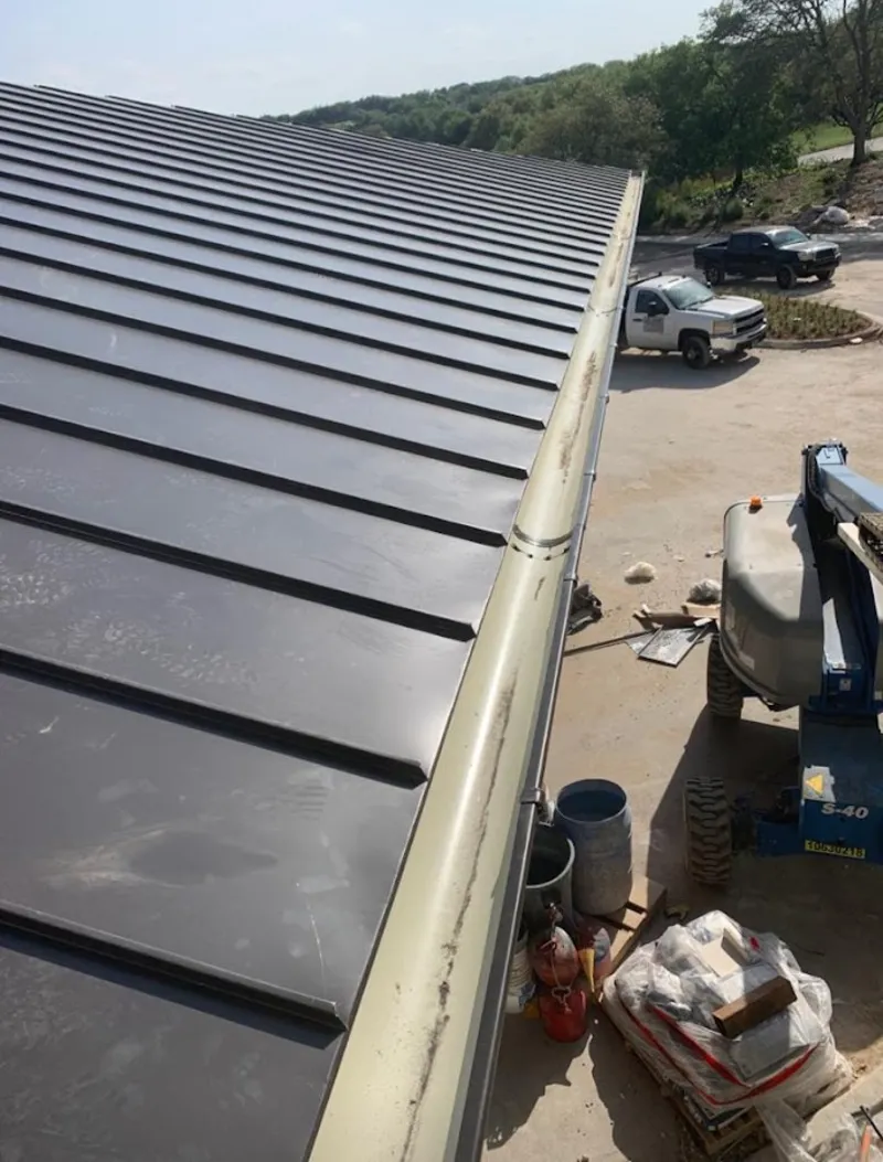 Standing seam panel and gutter detail on a metal roofing jobsite in Ferguson
